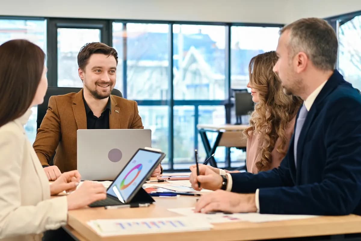 A B2B team discussing a proposal around a laptop in a meeting room